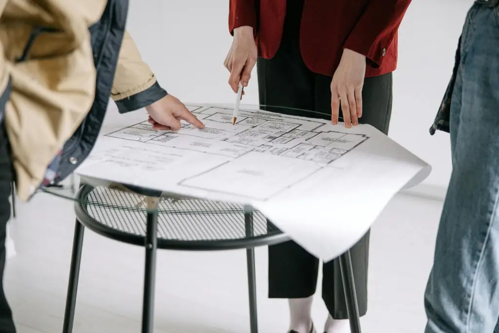 People discussing architectural floor plans during an interior design consultation.